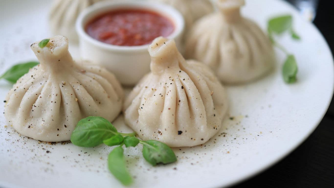 Steamed dumplings served with tomato dipping sauce