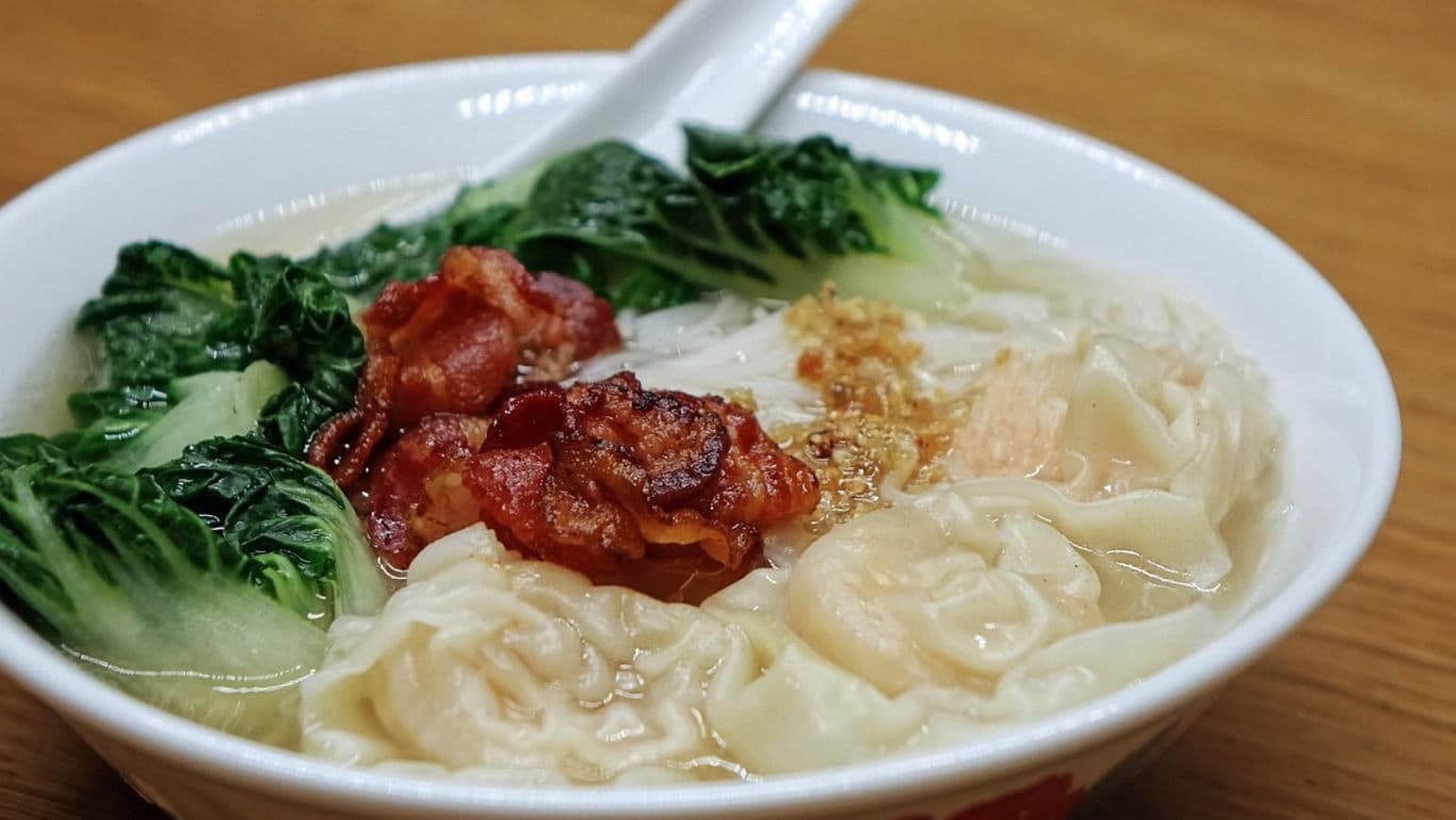 Bowl of wonton noodle soup with greens and pork