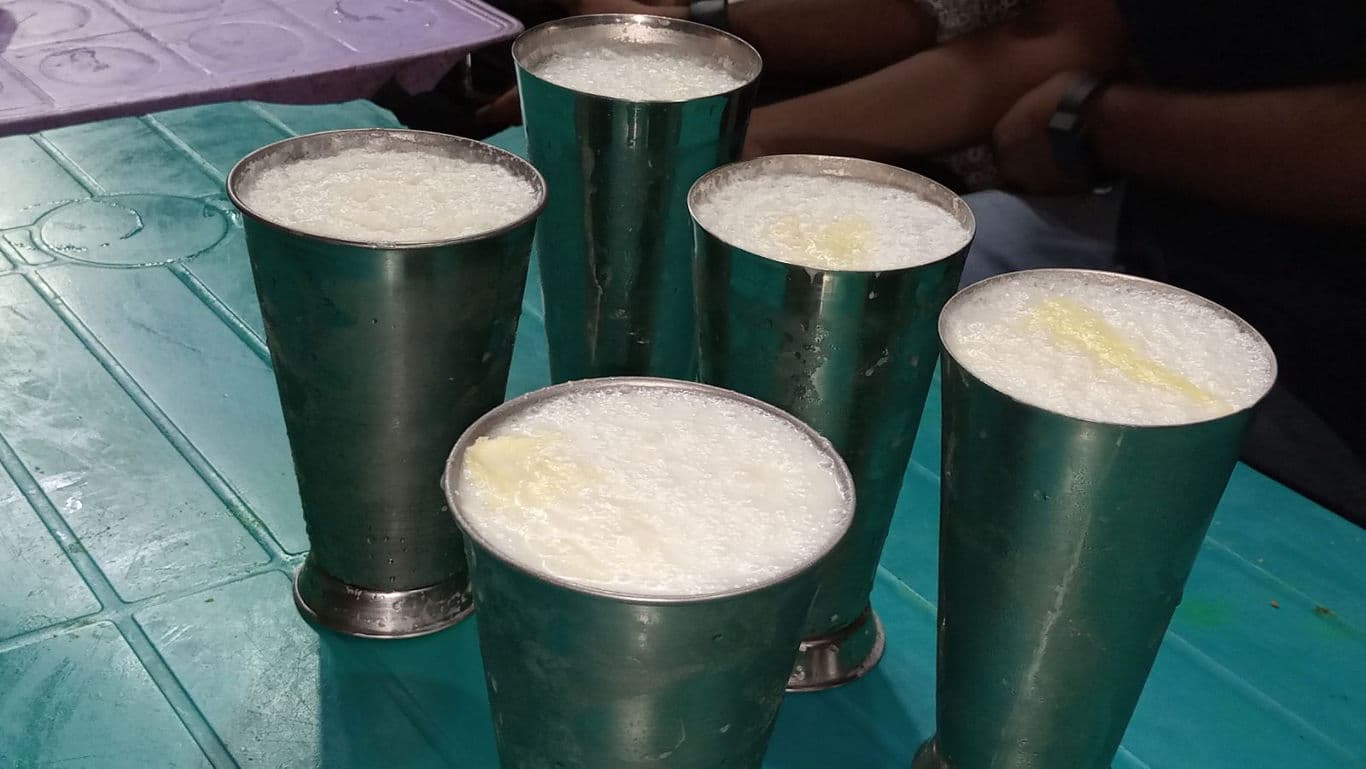 Five metal glasses of frothy beverage