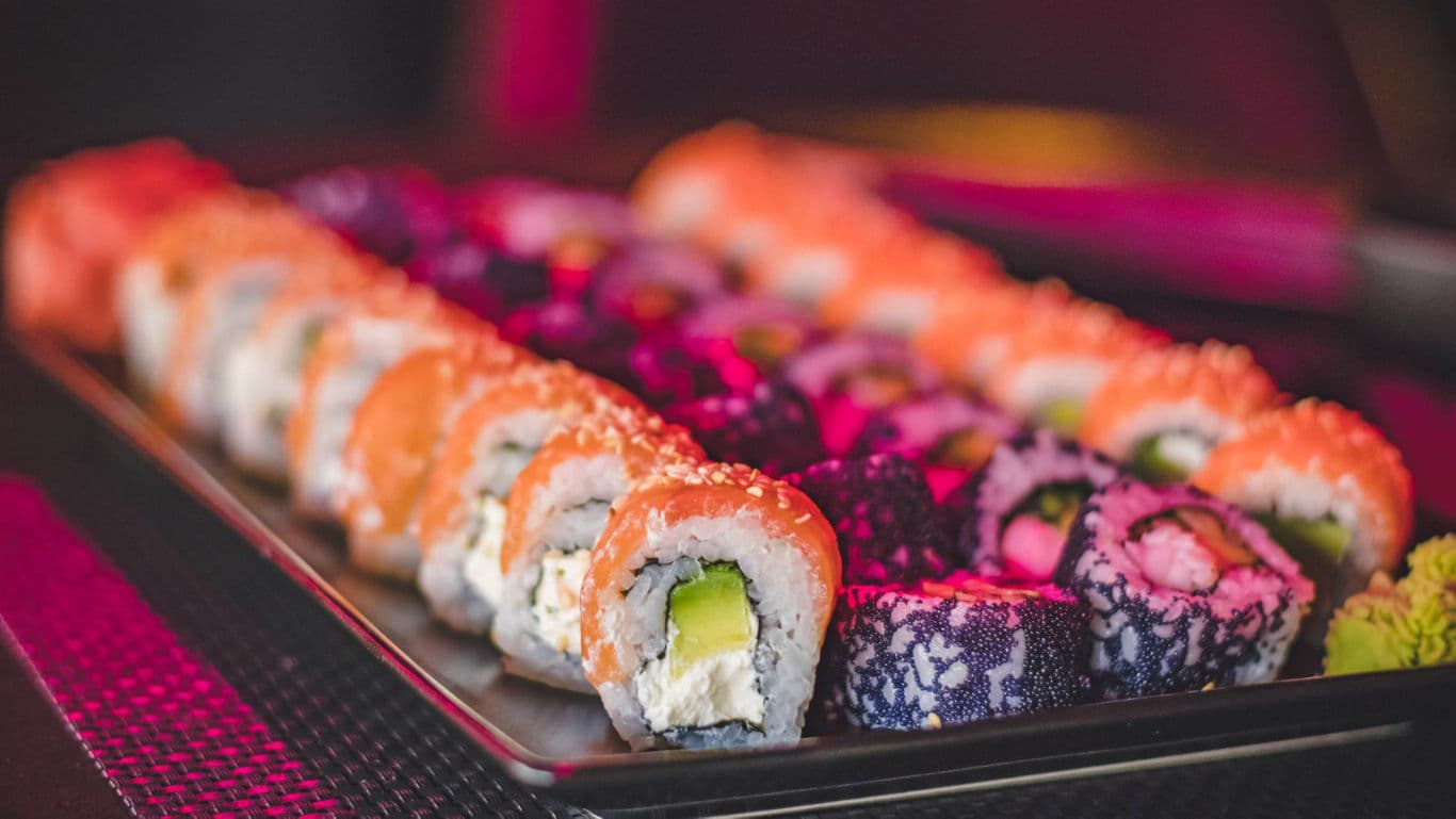 Colorful assorted sushi rolls on black serving tray