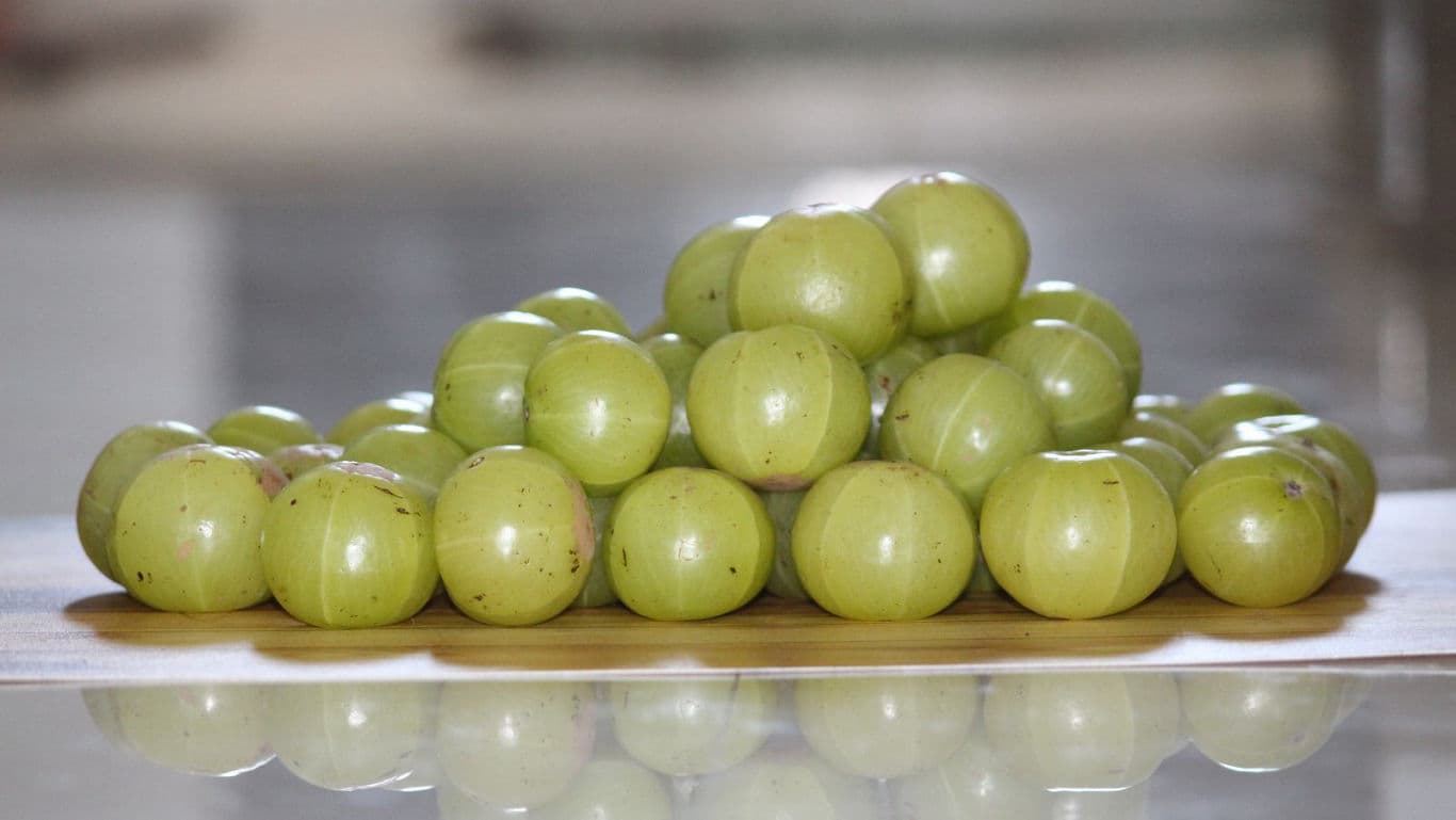 Fresh Indian gooseberries stacked on wooden surface