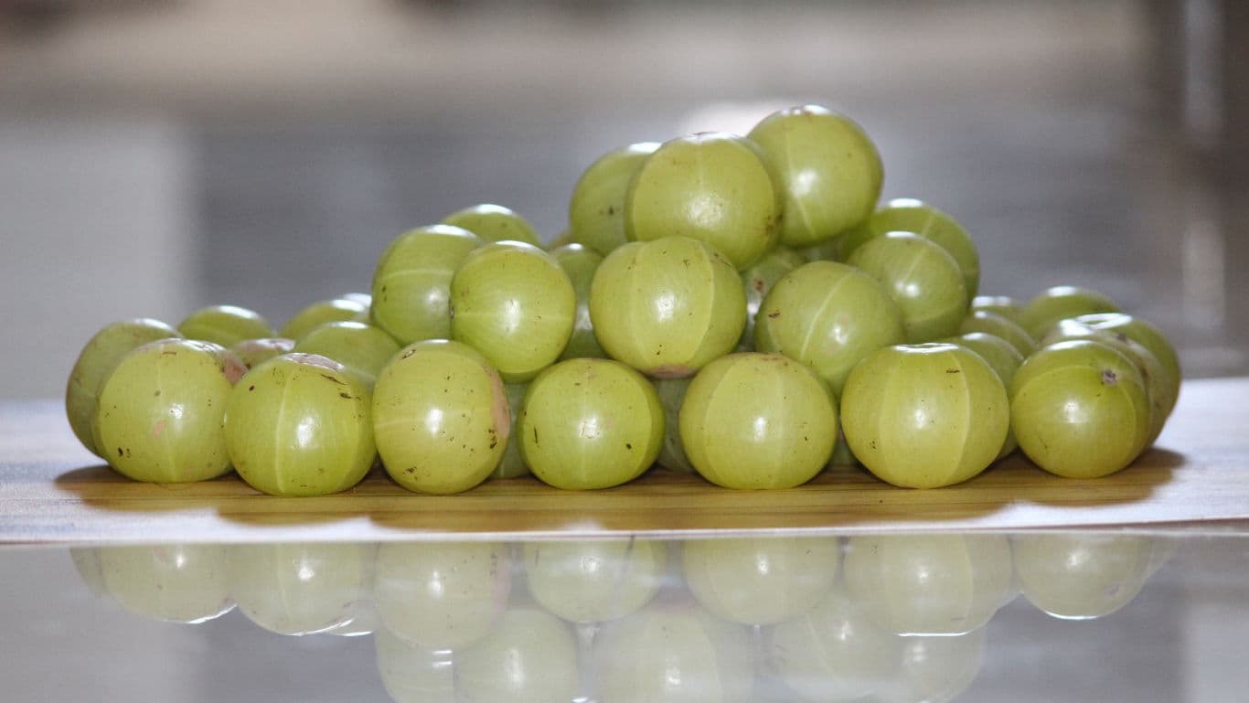 Fresh Indian gooseberries stacked on wooden surface