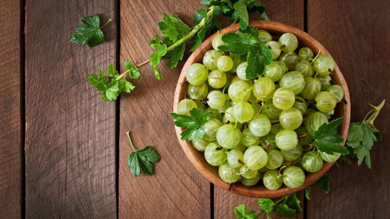 Fresh gooseberries in wooden bowl on rustic table