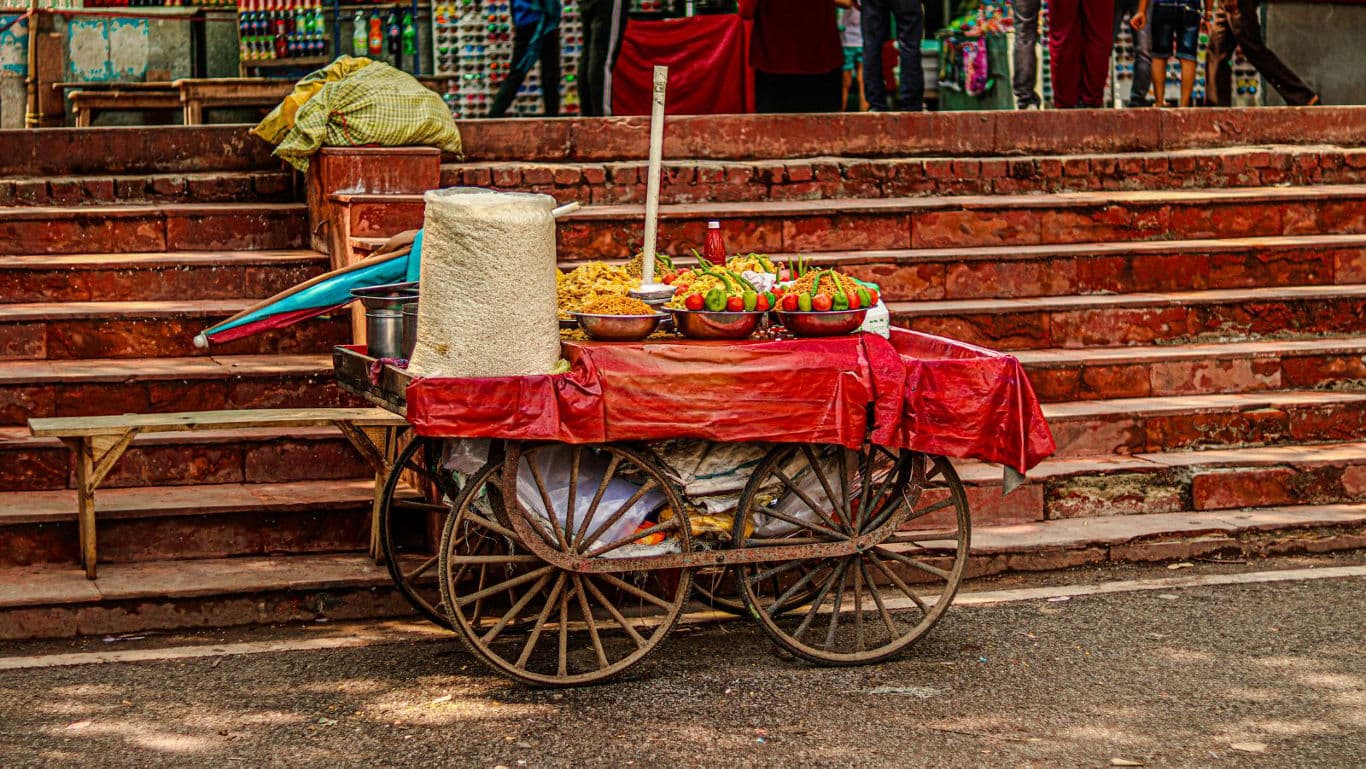 Street food cart with snacks near red stone steps