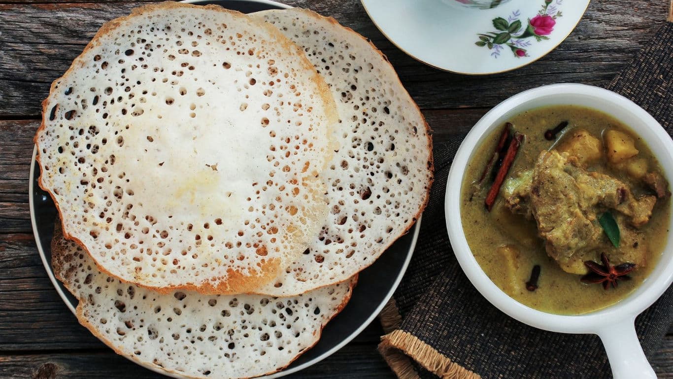 Traditional appam with curry served on table