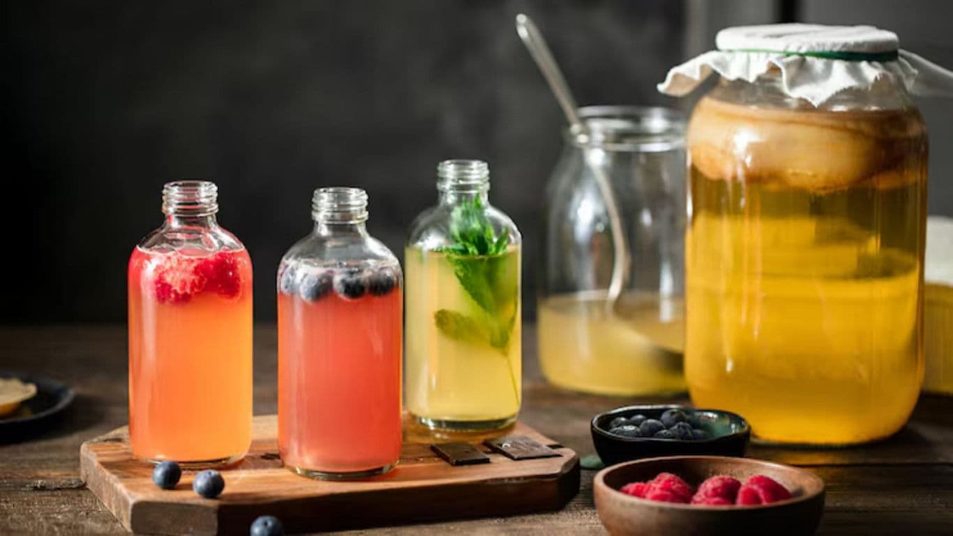 Assorted flavored kombucha bottles on wooden tray