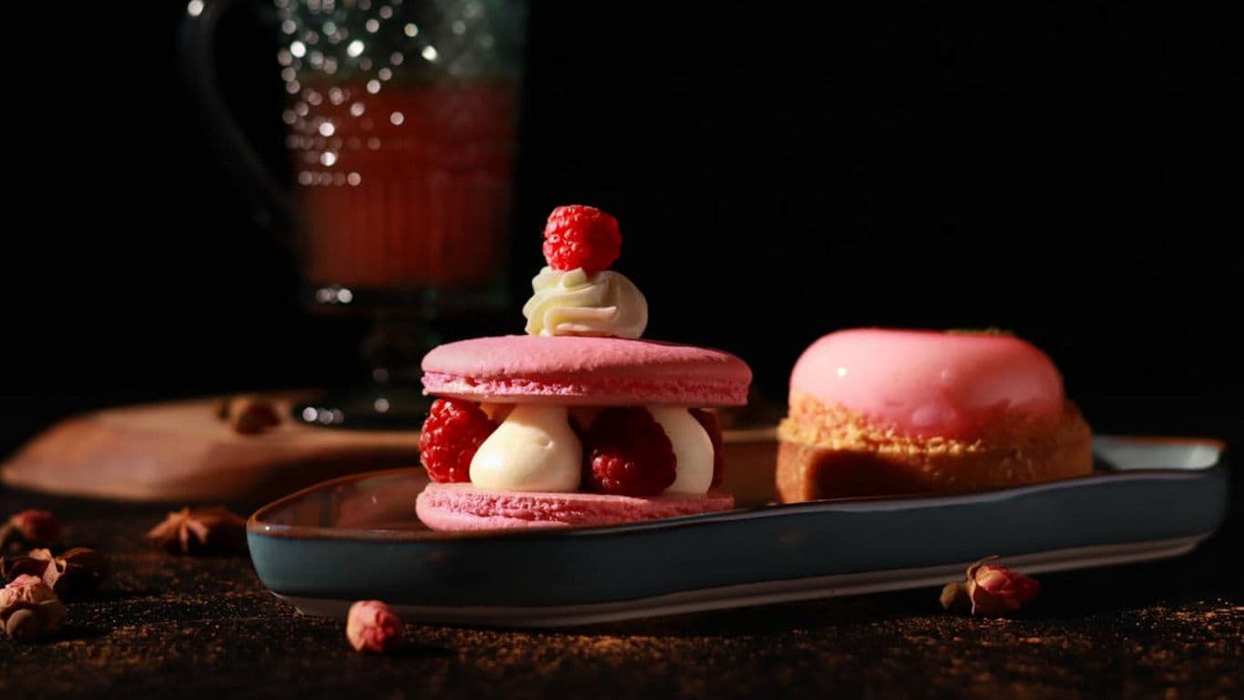 Pink macarons and dessert on dark plate