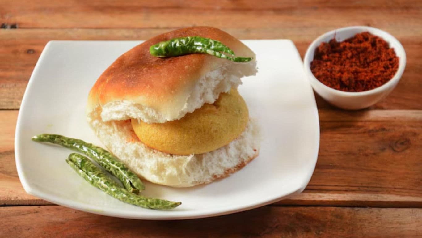 Indian vada pav with fried green chilies on plate
