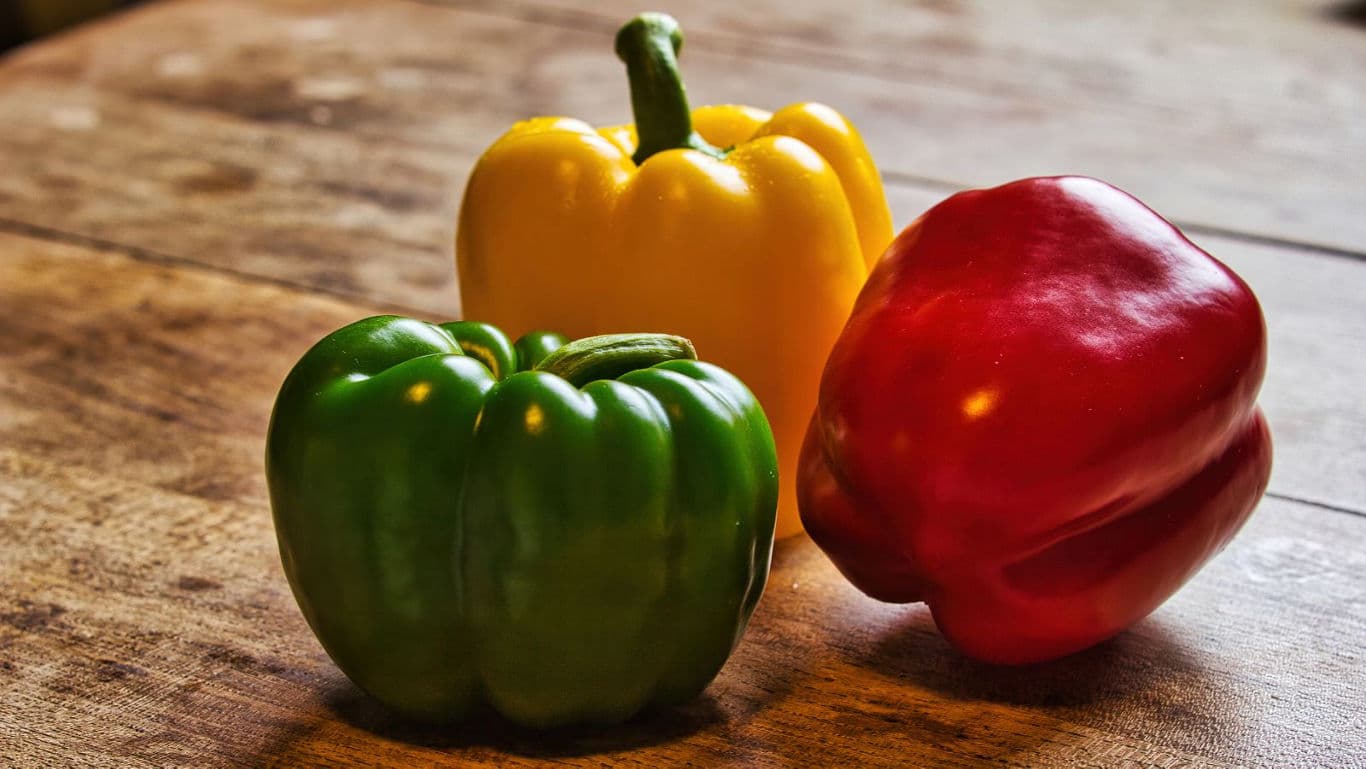 Colorful bell peppers on rustic wooden table