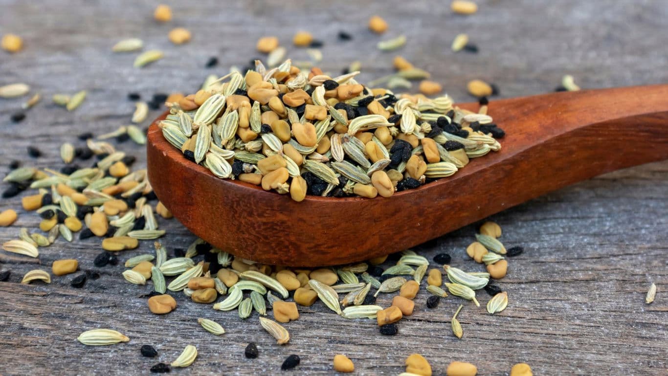Wooden spoon with mixed seeds on table