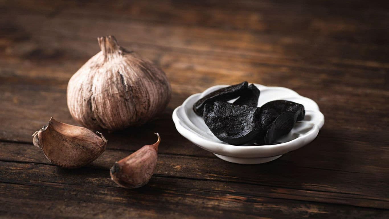 Black garlic cloves on rustic wooden table