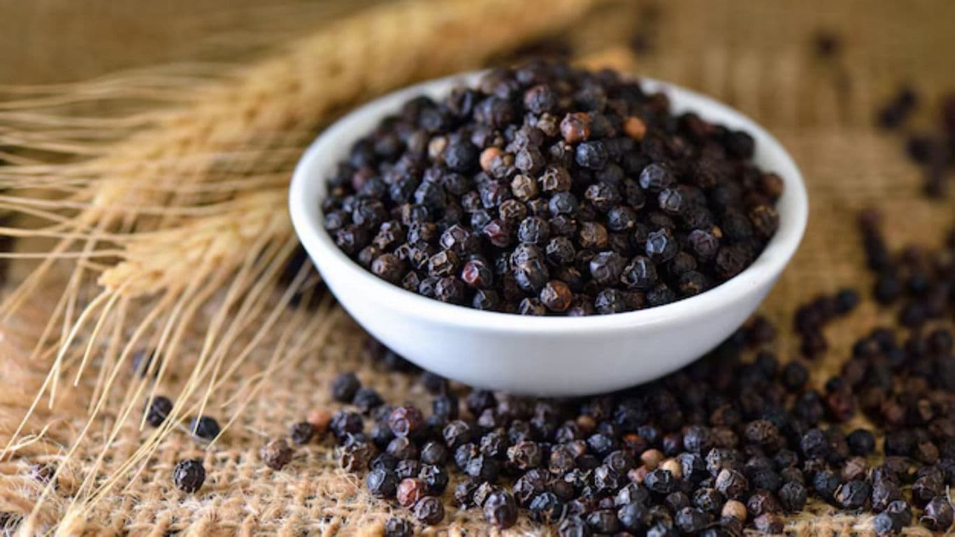 Black peppercorns in white bowl on burlap