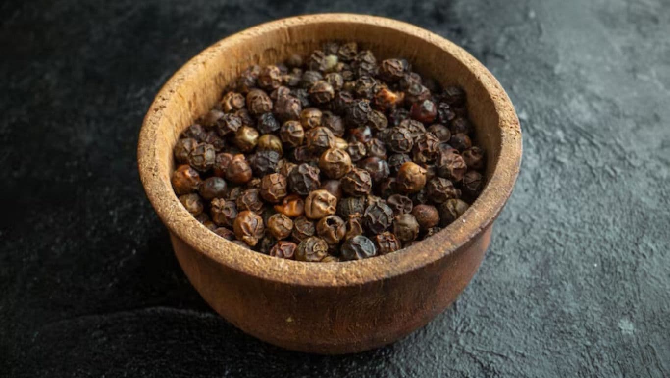 Wooden bowl filled with black peppercorns