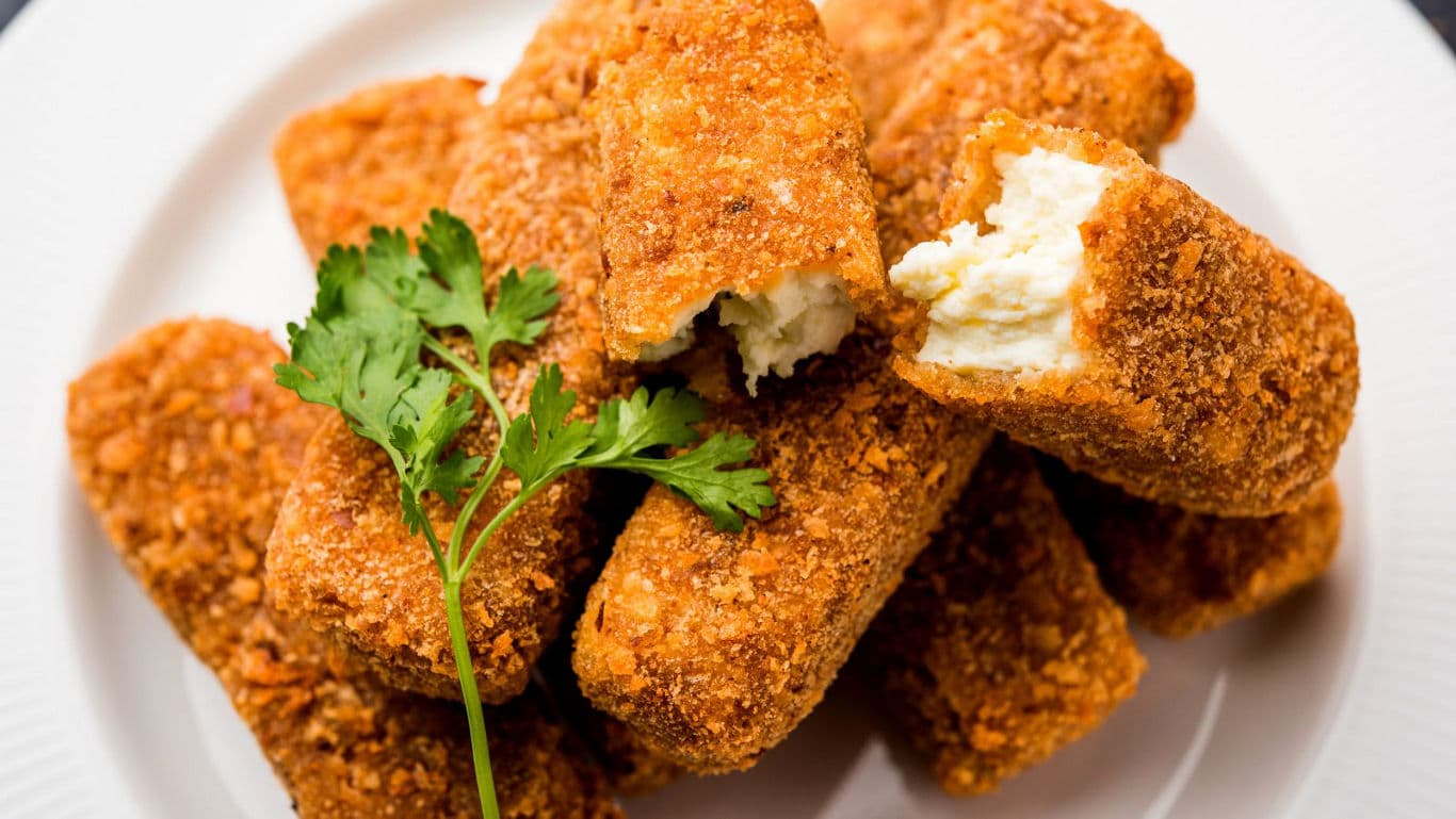 Golden breaded cheese sticks on white plate