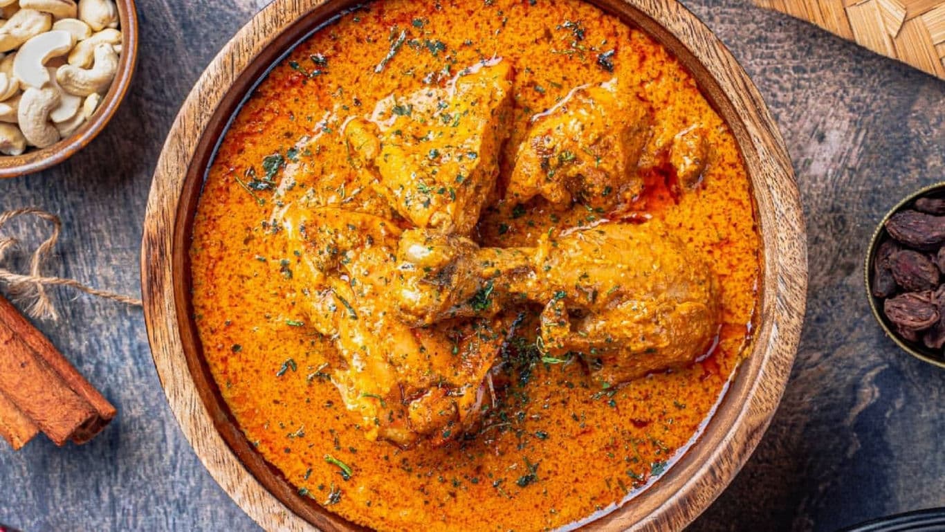 Traditional Indian chicken curry in wooden bowl overhead