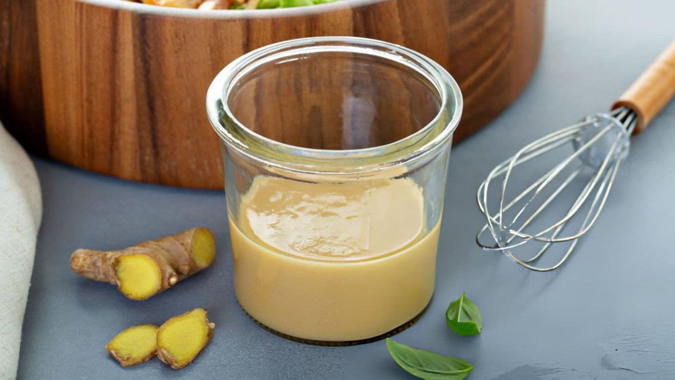 Glass jar of ginger dressing with whisk