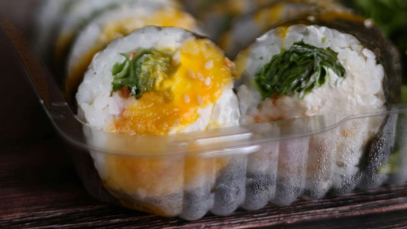 Close-up of assorted sushi rolls in plastic tray