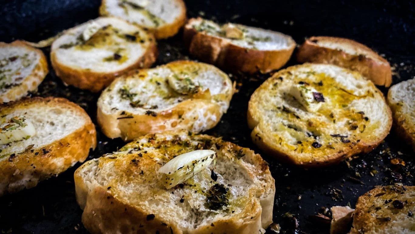 Garlic bread slices with herbs on skillet