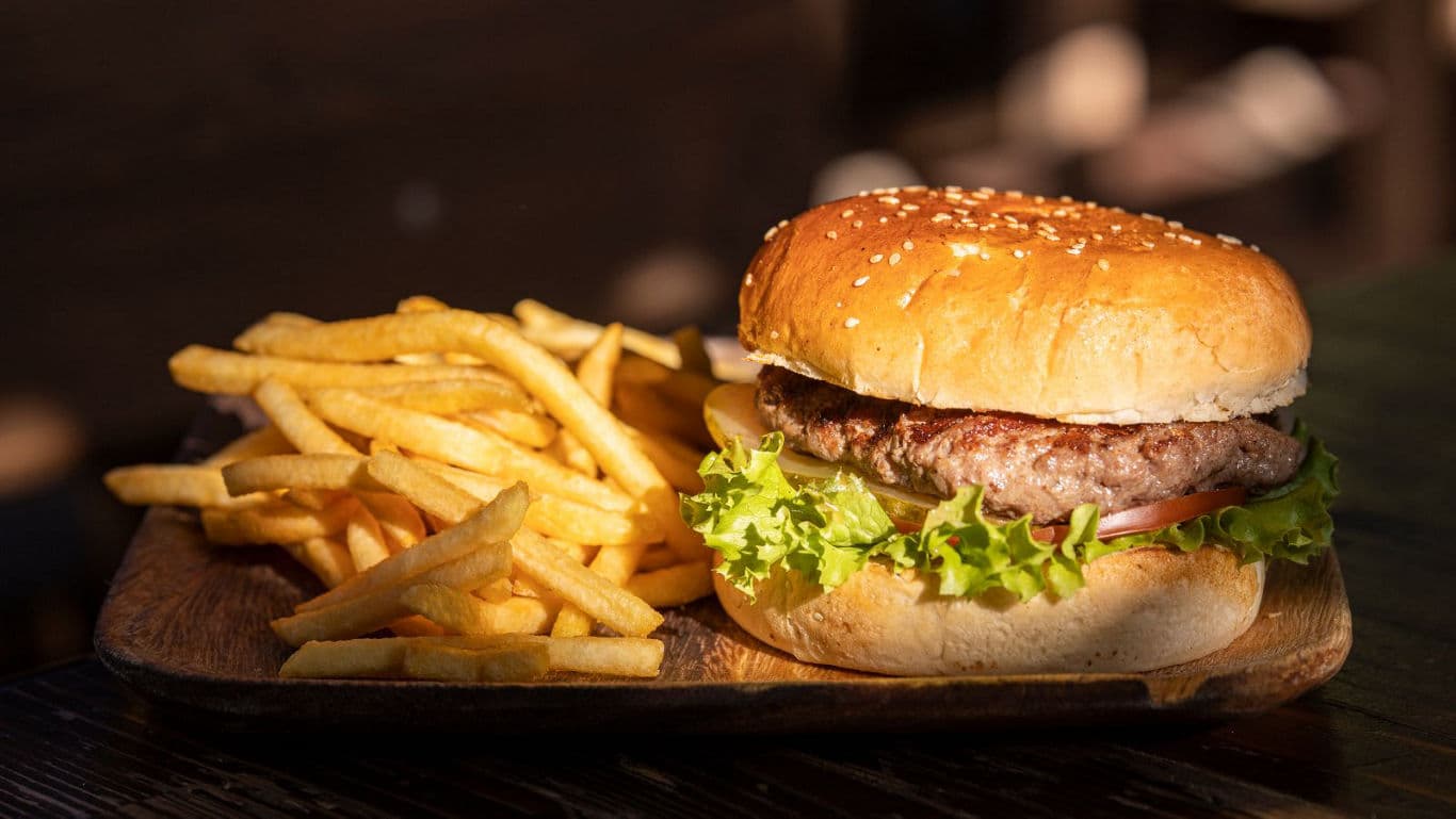 Classic hamburger with fries on wooden plate
