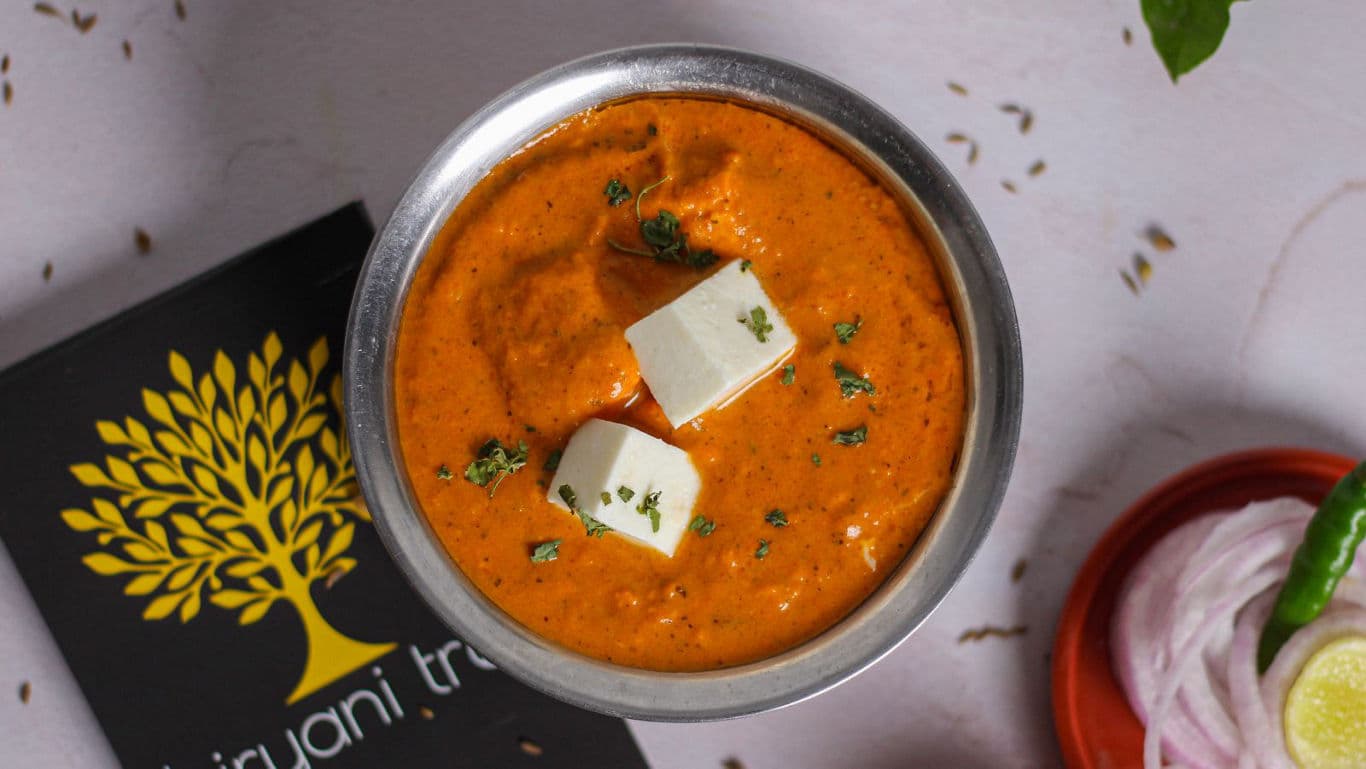 Paneer curry in steel bowl with garnish