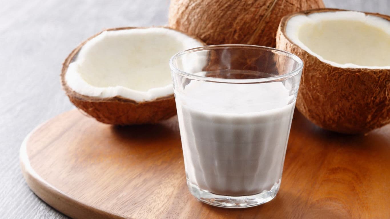 Fresh coconut milk in glass with coconuts