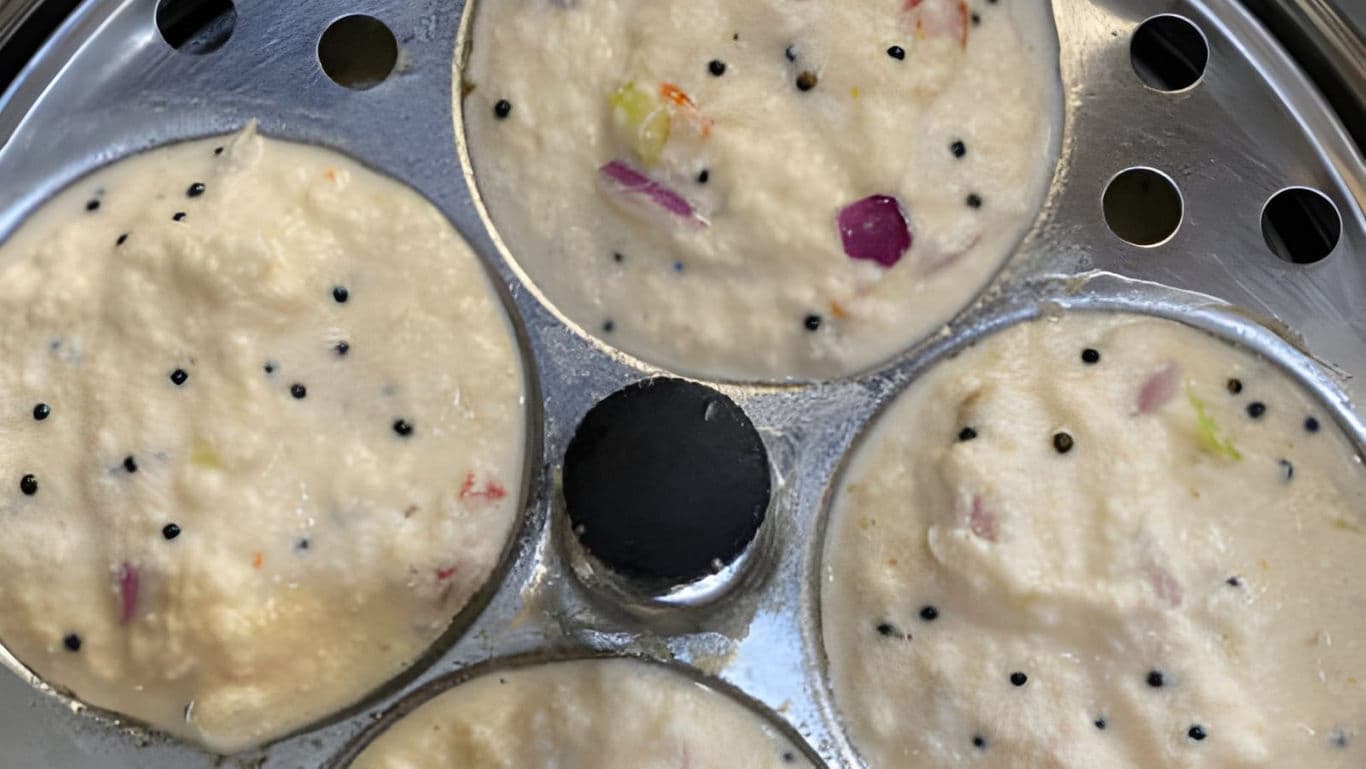 Idli batter in steaming tray with vegetables