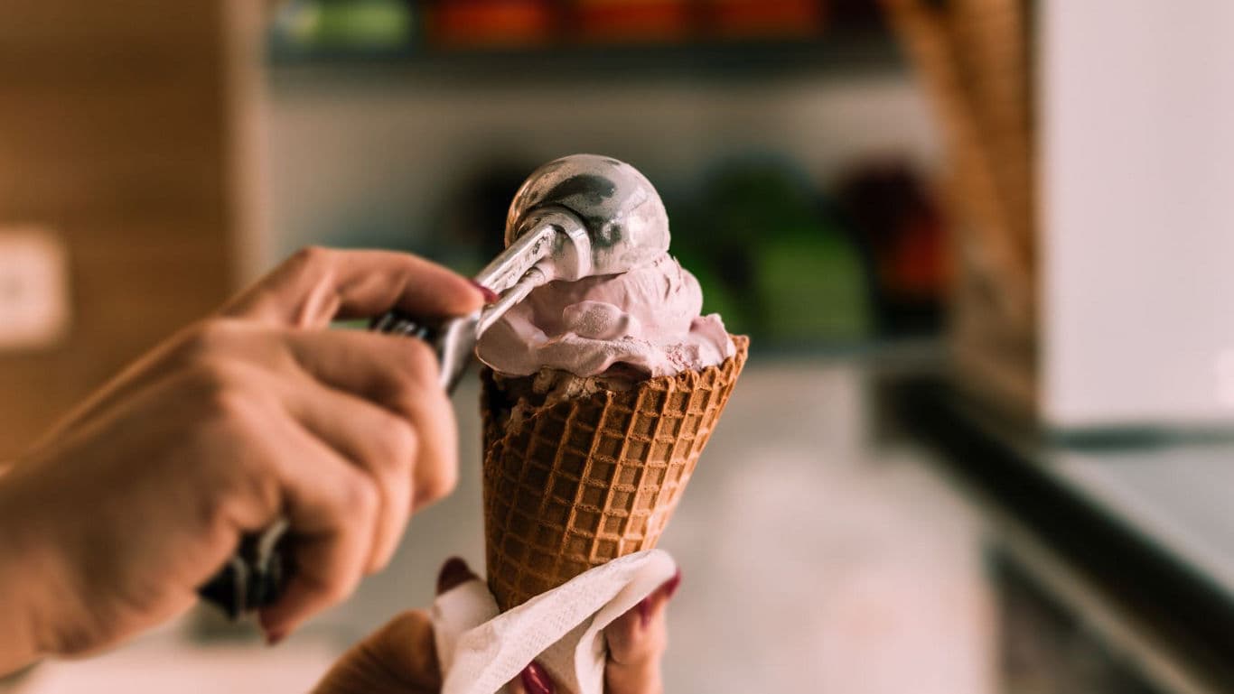 Hand scooping ice cream into waffle cone