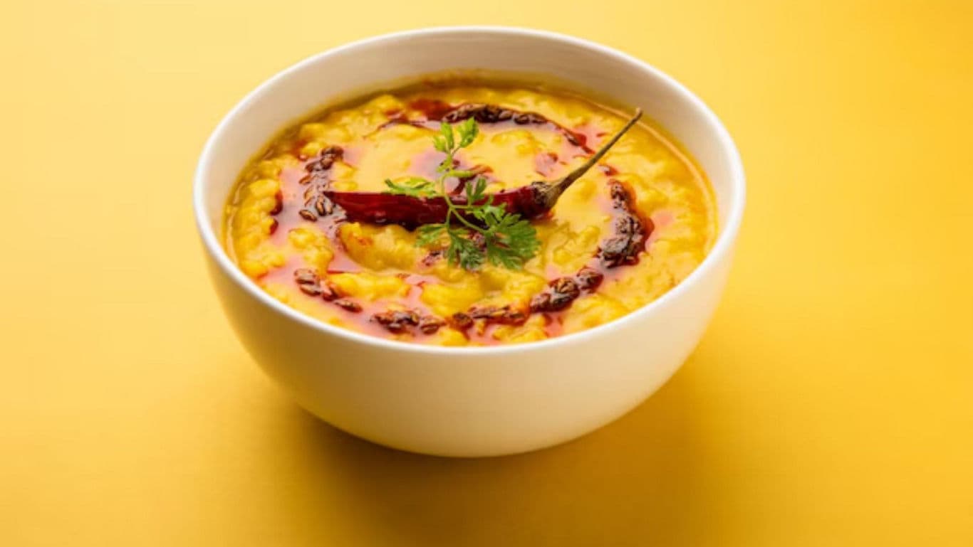 Bowl of lentil curry on yellow background
