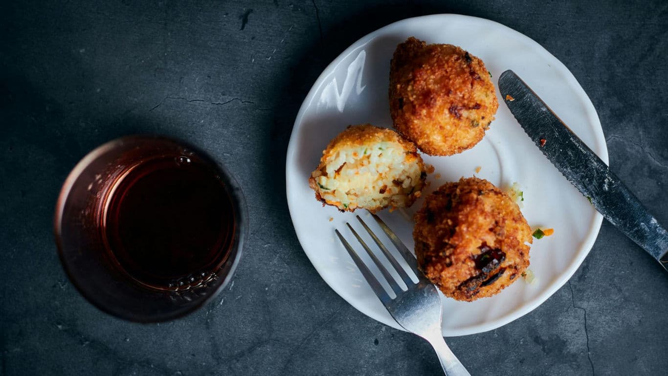 Crispy arancini with drink on table