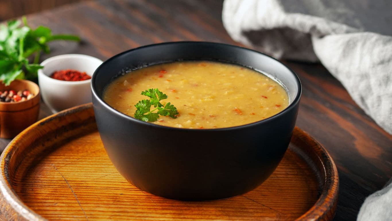 Warm lentil soup in black bowl