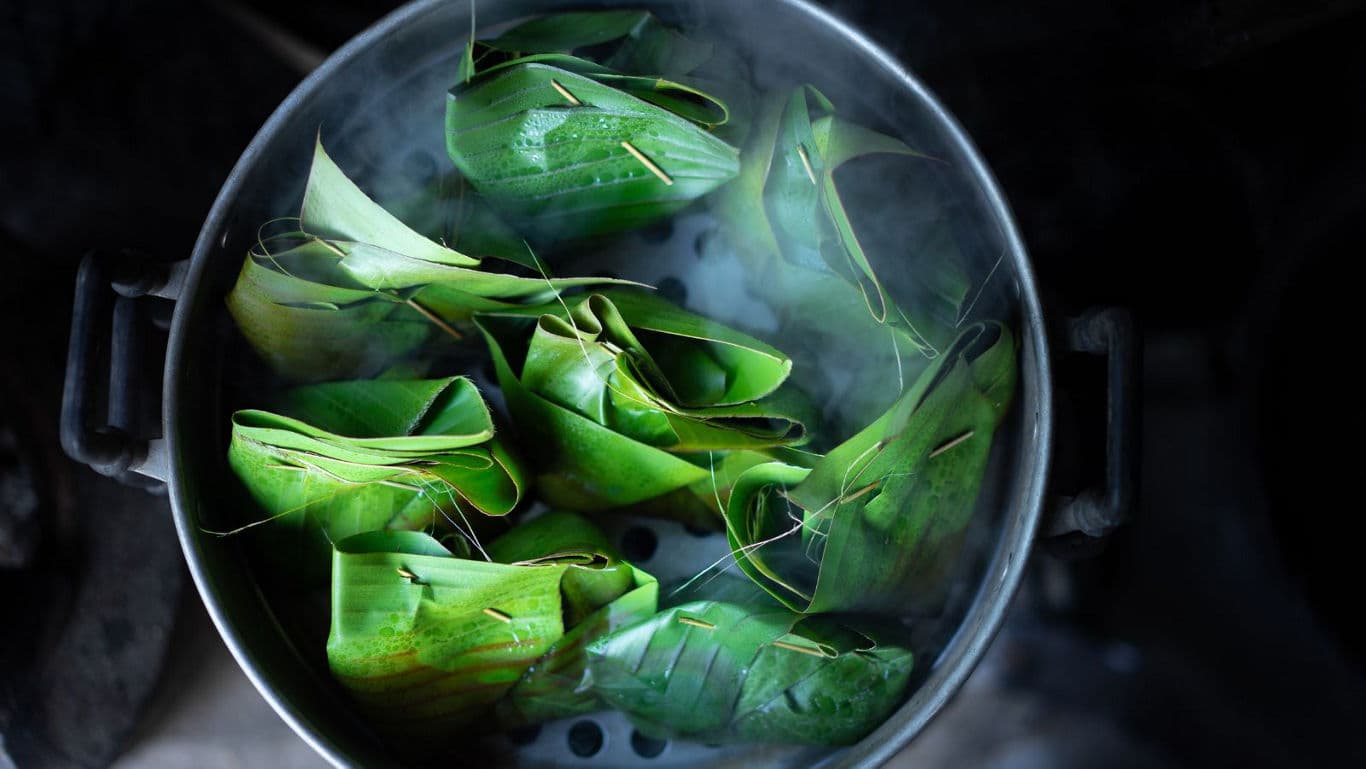 Steamed banana leaf parcels cooking in pot