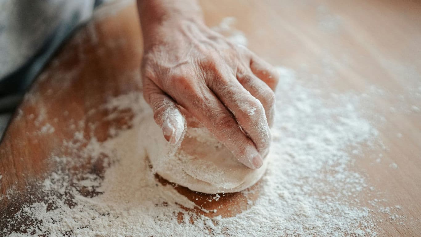 Hand Kneading Dough on Floured Wooden Surface