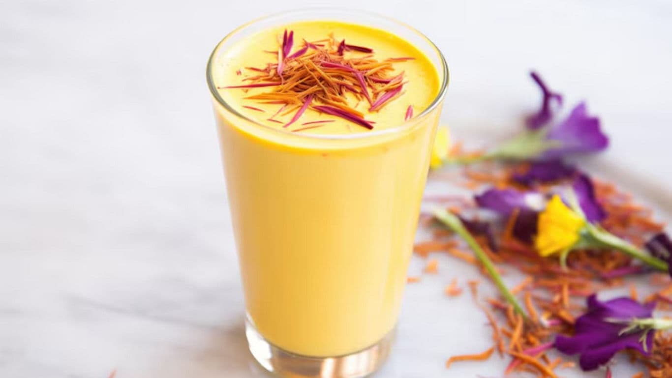 Glass of saffron mango lassi with flowers