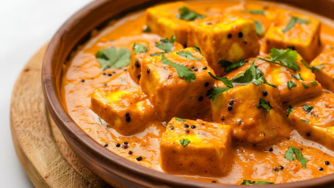 Paneer cubes in creamy orange curry sauce