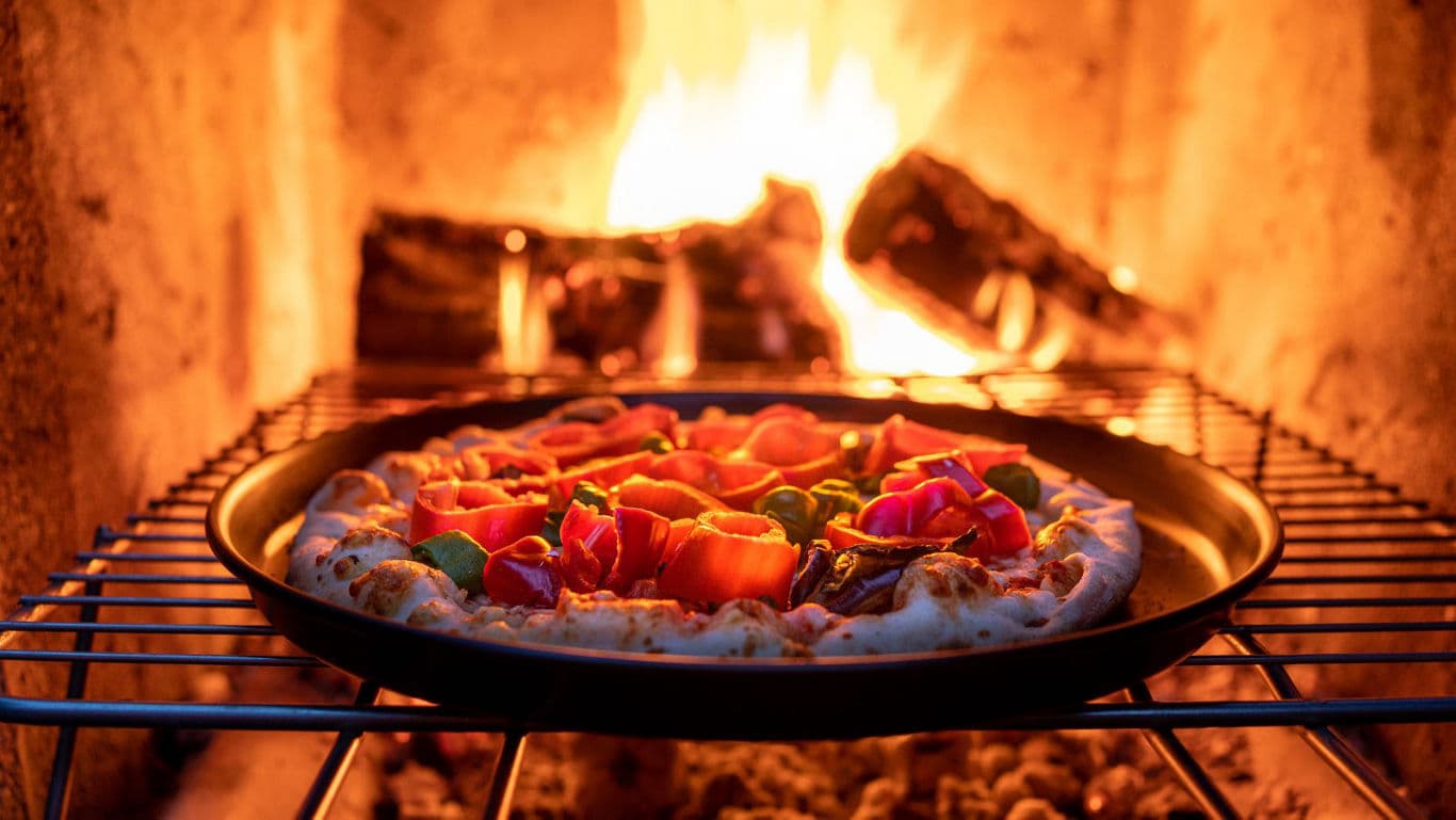 Fresh vegetable pizza baking in wood-fired oven