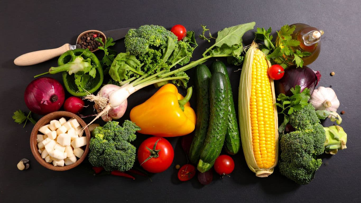 Fresh assorted vegetables and herbs on dark table