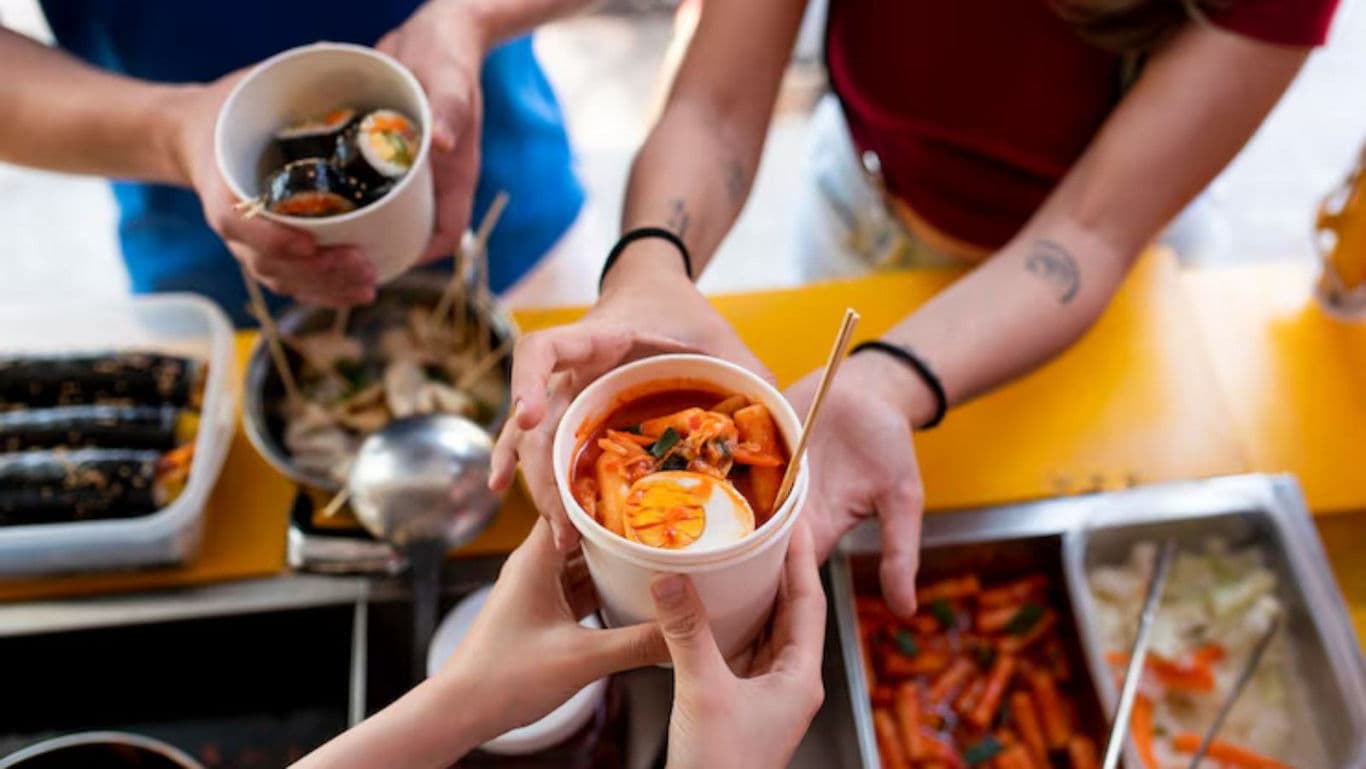 Hands Sharing Korean Street Food at Outdoor Market