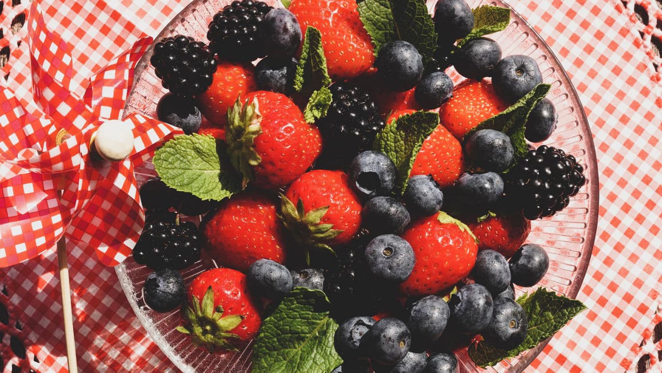 Fresh berries in glass bowl on checkered cloth