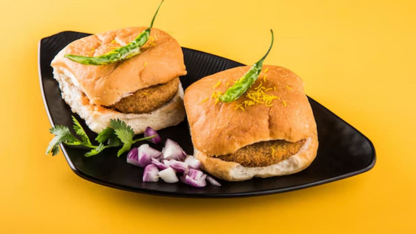 Indian vada pav with green chili on black plate
