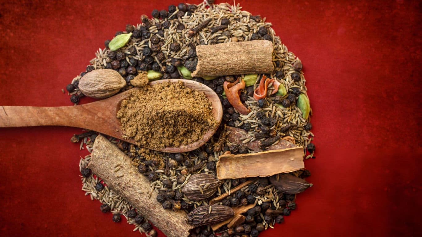 Assorted spices with wooden spoon on red