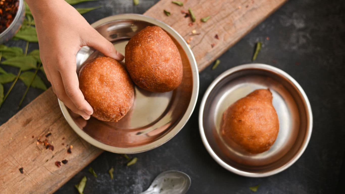 Hand picking fried snacks in metal bowl