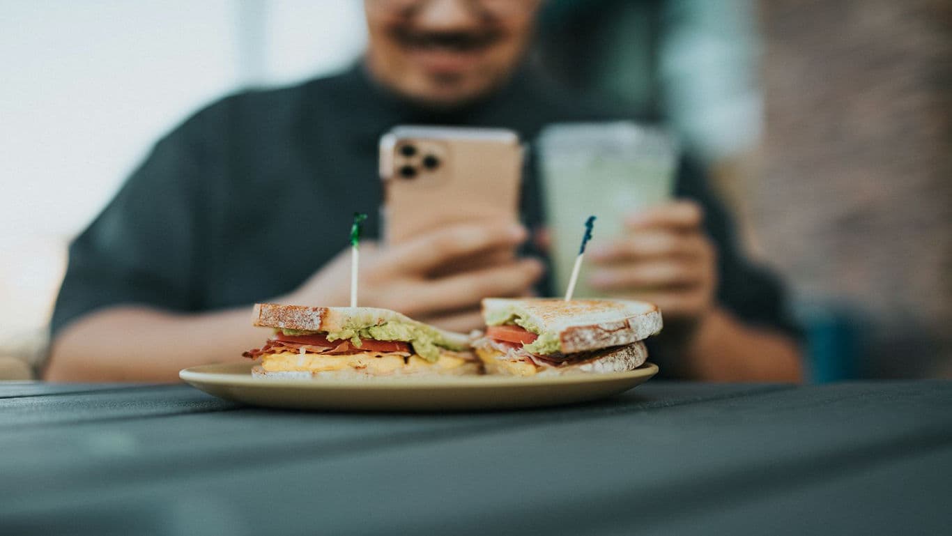 Close-up of sandwich with man using phone