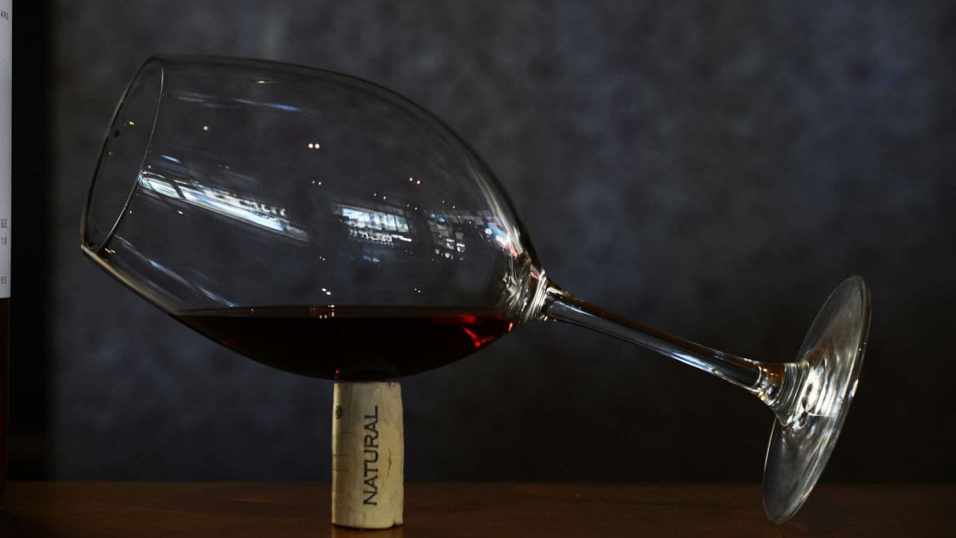Wine glass balanced on cork with red wine