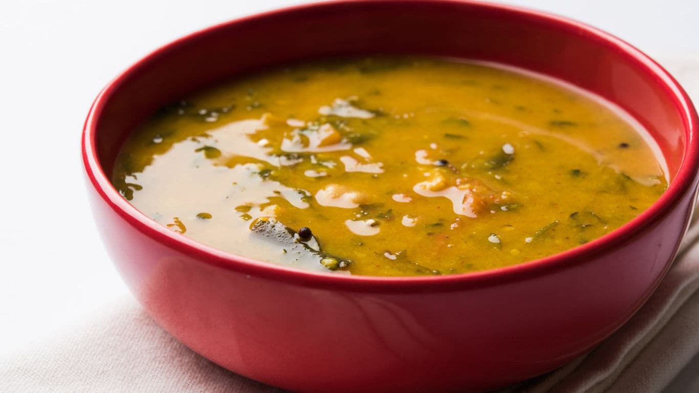Yellow lentil soup served in a red bowl