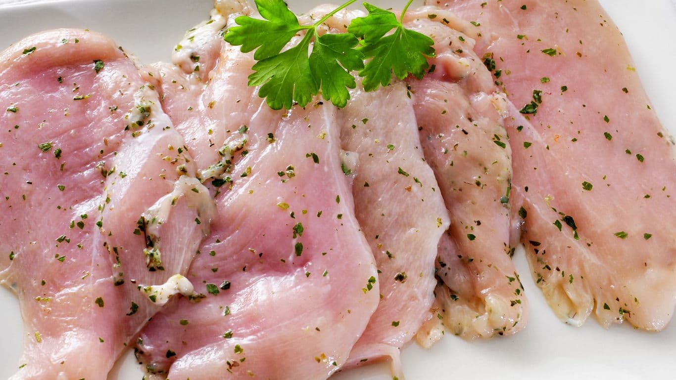Raw marinated chicken fillets garnished with parsley