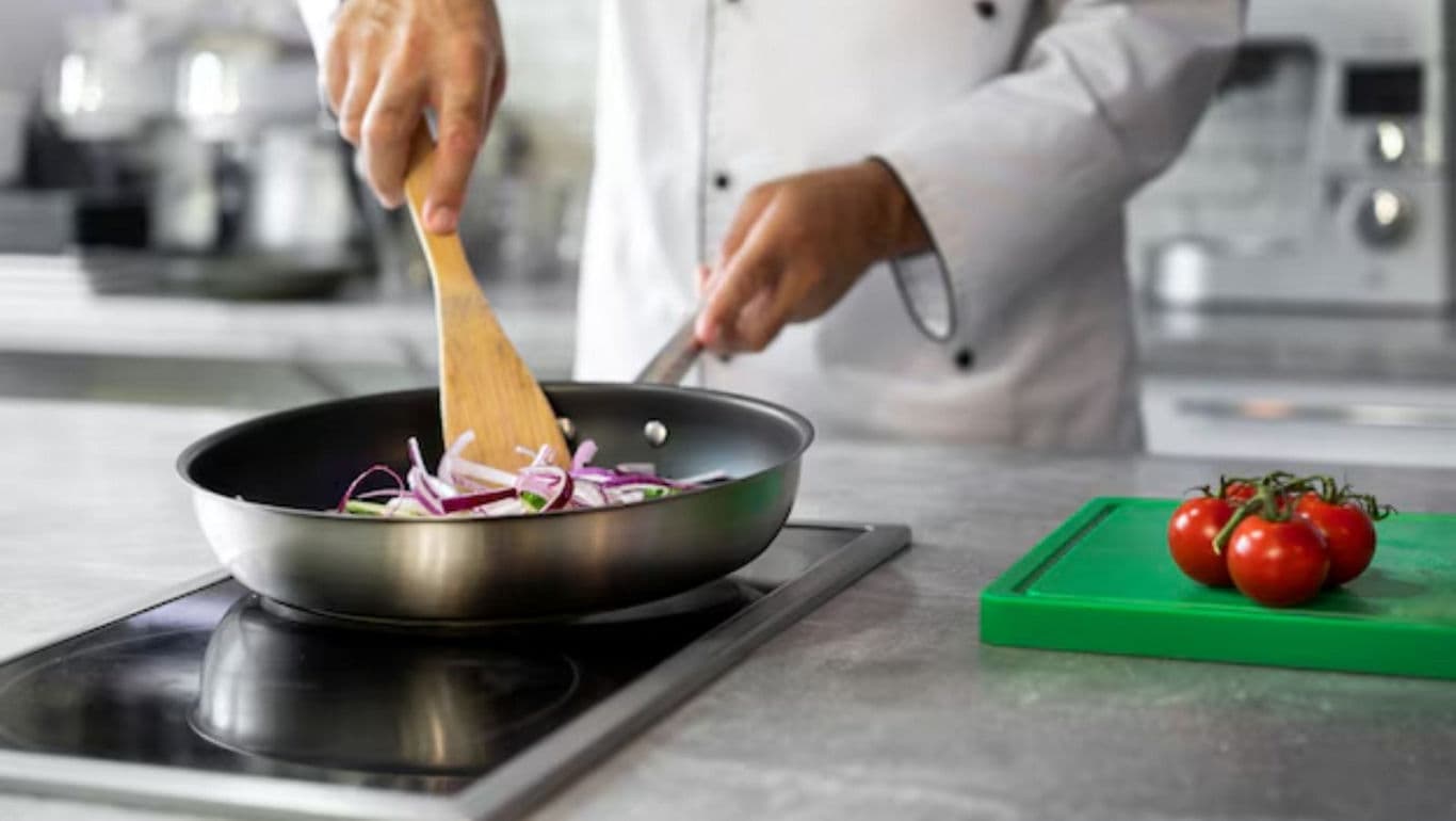 Chef cooking onions in frying pan