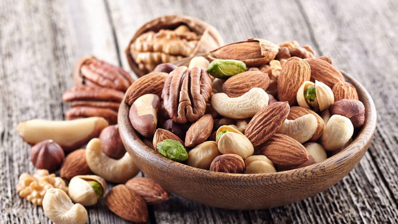 Assorted nuts in wooden bowl on rustic table