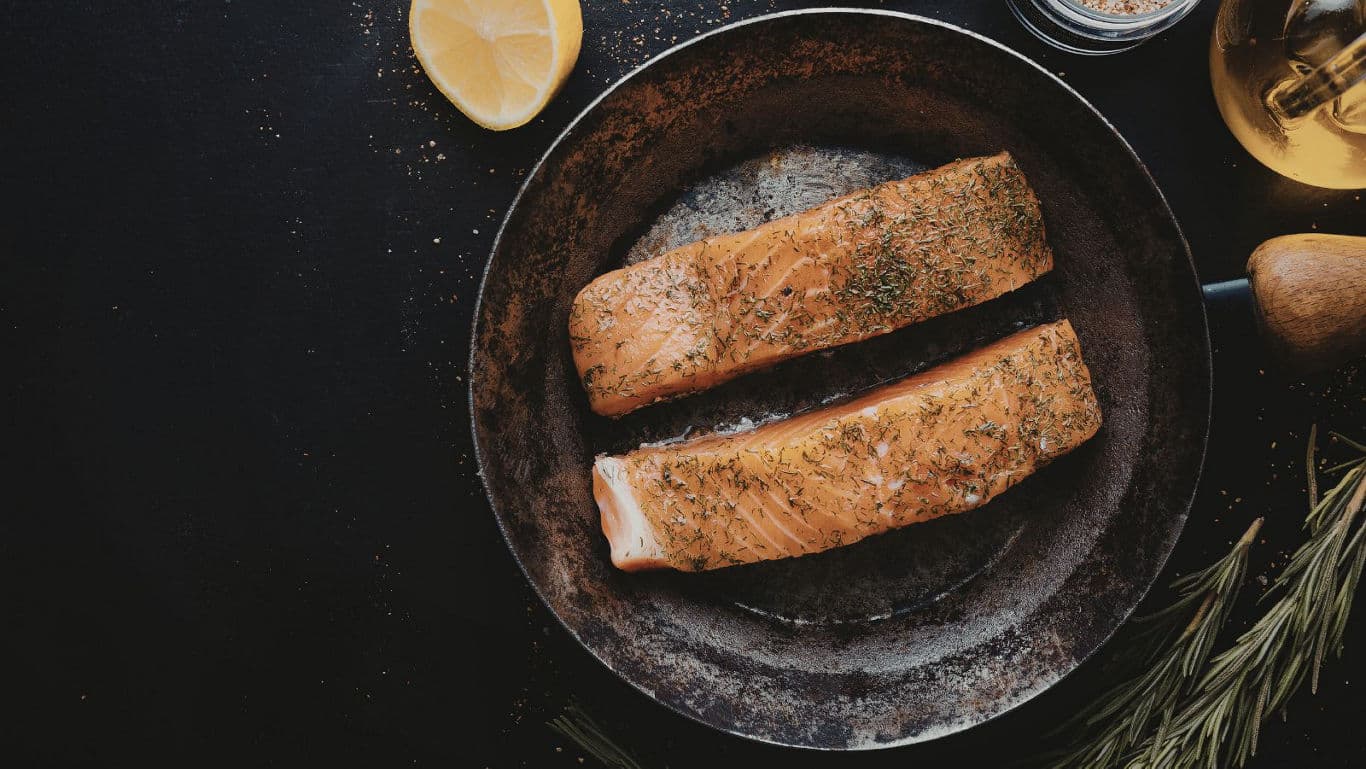 Seasoned salmon fillets in rustic frying pan