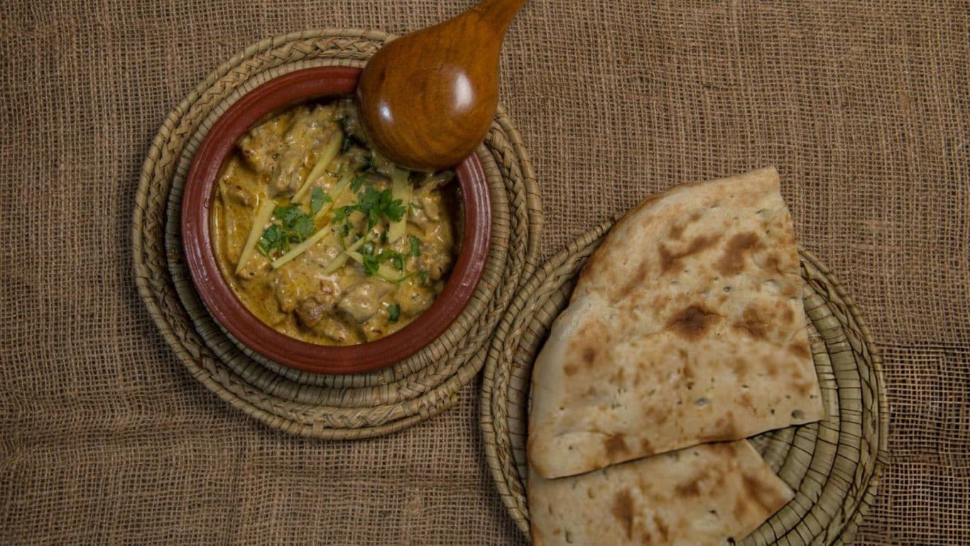 Traditional curry with naan bread on burlap