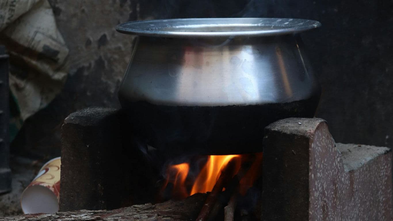 Stainless steel pot cooking over open wood fire